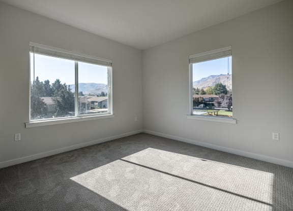 an empty living room with two windows and a rug at Sagecrest Apartments, Washington, 98801