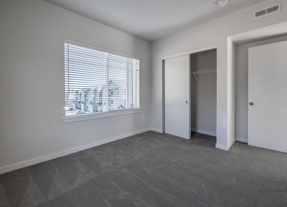 an empty living room with a large window and a door to a closet at Sagecrest Apartments, Wenatchee, WA, 98801