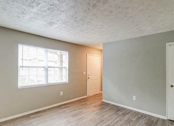 A room with a window, two doors, and a wooden floor.at Waverly Manor Townhomes, Georgia  