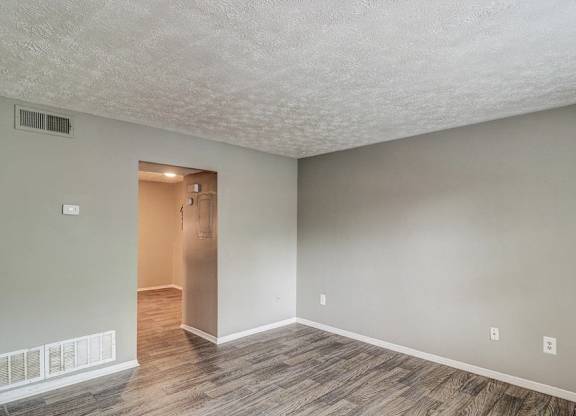 A room with a wooden floor and a white wall with a doorway leading to another room.at Waverly Manor Townhomes, Norcross Georgia  