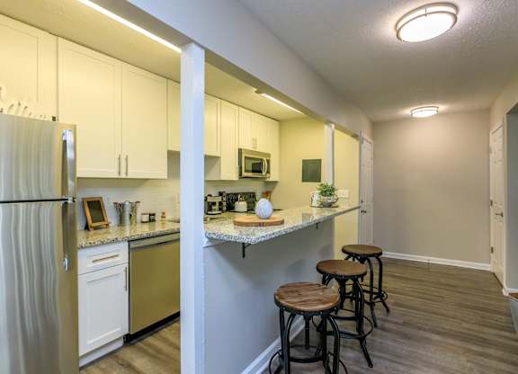 A kitchen with white cabinets and a refrigerator.