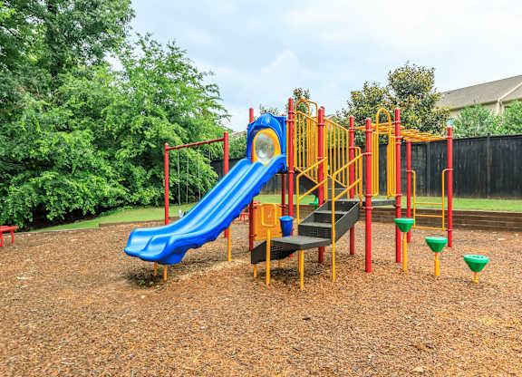 A playground with a blue slide and yellow and red play structures.