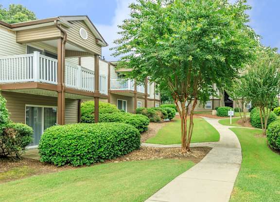 A tree in a grassy area in front of a building.
