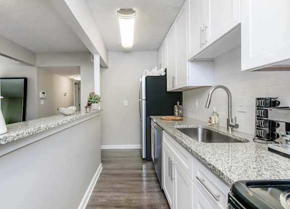 A kitchen with a black fridge and white cabinets.