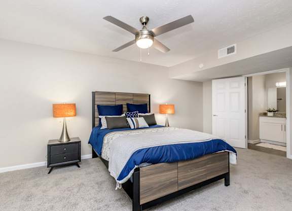 A bedroom with a bed, nightstands, and a ceiling fan.