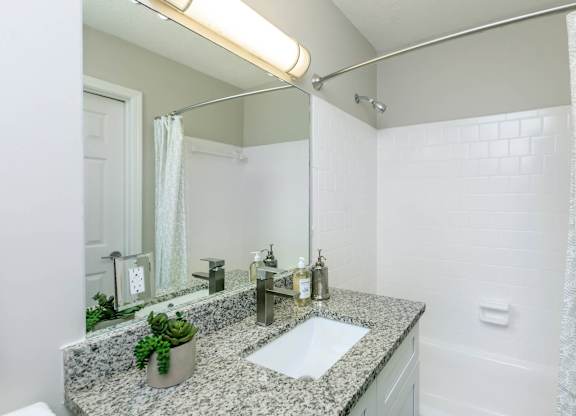 A bathroom with a granite countertop and a white sink.