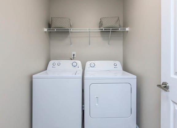 Two white washing machines in a laundry room.