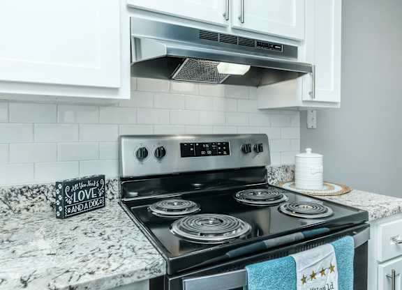 A black stove top with a pot on it and a sign that says at Crest at East Cobb Apartments, Marietta