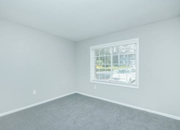 A room with a window and a grey carpet at Crest at East Cobb Apartments, Georgia