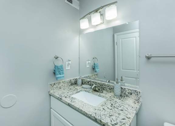 A bathroom with a marble countertop and a white sink at Crest at East Cobb Apartments, Georgia, 30062