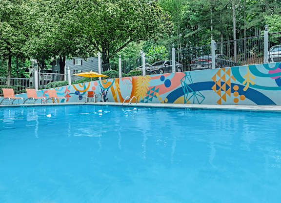 A pool with a blue water surface and a colorful mural on the side at Crest at East Cobb Apartments, Marietta, Georgia