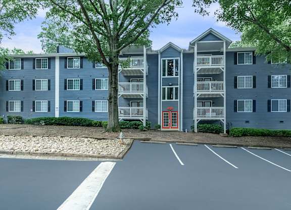 A large grey apartment building with a red door in front at Crest at East Cobb Apartments, Marietta, GA, 30062