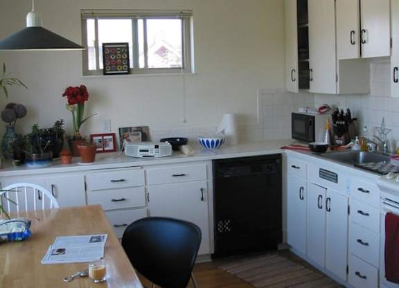 A kitchen with white cabinets and a black chair.