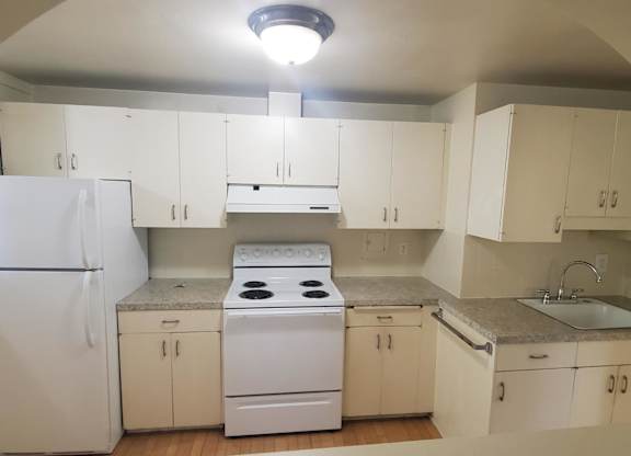 A kitchen with white appliances and cabinets.