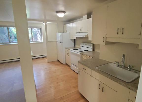 A kitchen with white cabinets and a wooden floor.