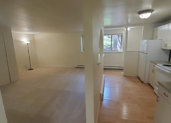 A kitchen with white appliances and wooden floors.