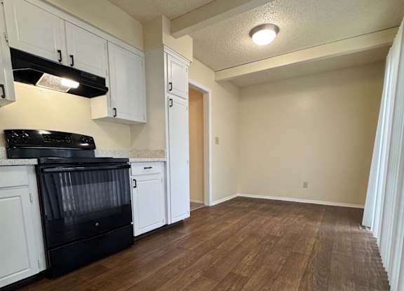 A kitchen with white cabinets and a black stove top oven.