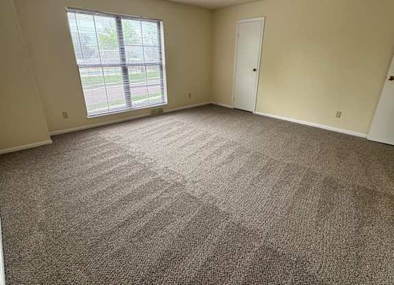 A room with a carpeted floor and a window.