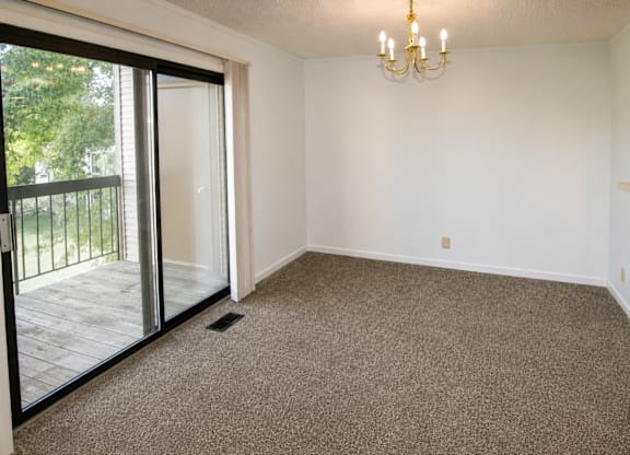 A room with a chandelier and sliding glass doors.