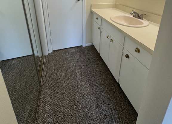 A bathroom with a sink, mirror, and cabinets.