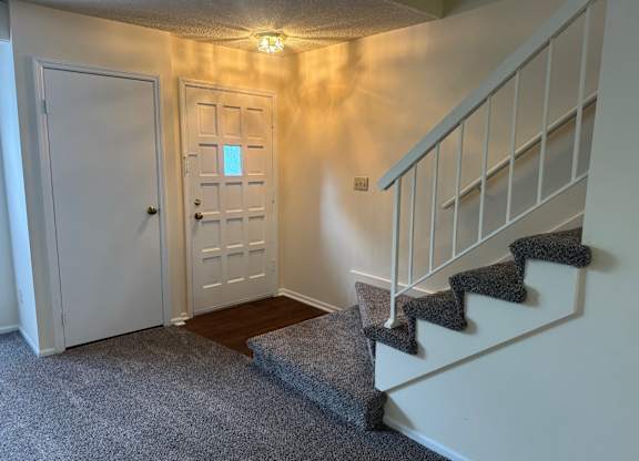 A hallway with a staircase and two doors.