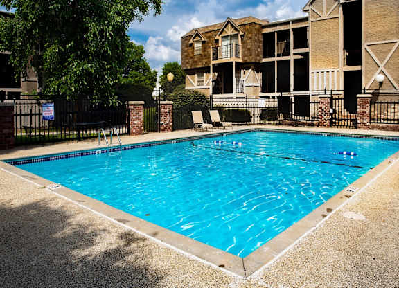 A swimming pool in front of a building with a fence around it.