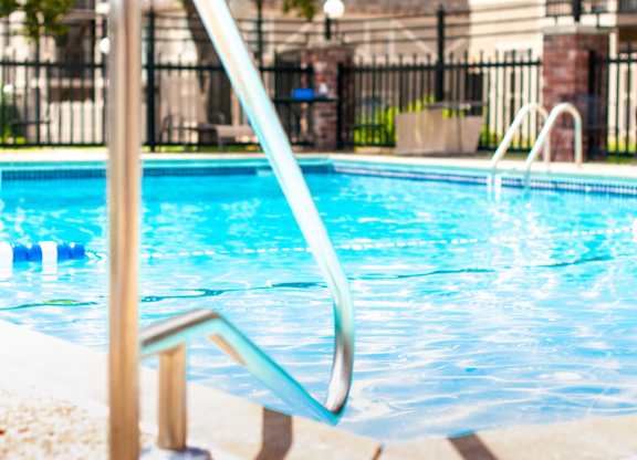 A pool with a diving board and a metal railing.