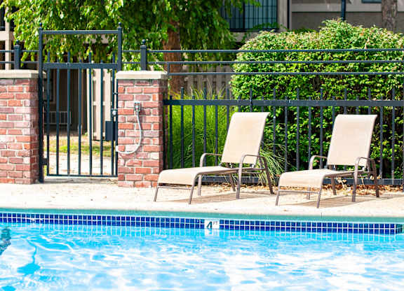 Two chairs are placed on the edge of a pool.