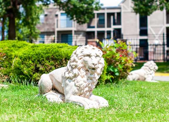 A white lion statue is sitting on the grass in front of a building.