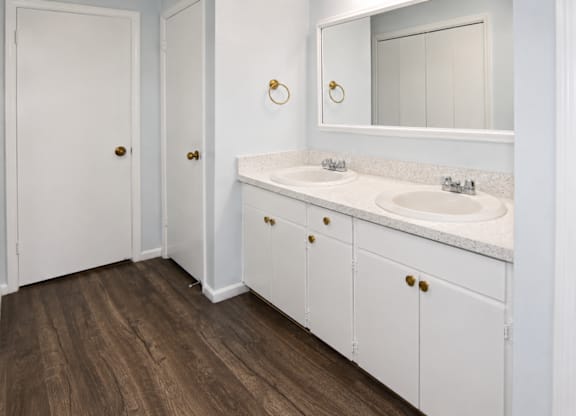 A white bathroom with a double sink and a mirror.