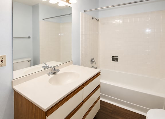 A white sink with a wooden counter top and a white toilet in a bathroom.