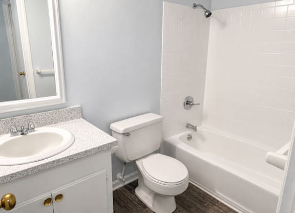 A white toilet sits next to a white bathtub in a bathroom.