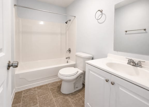 A white toilet sits next to a bathtub in a bathroom.