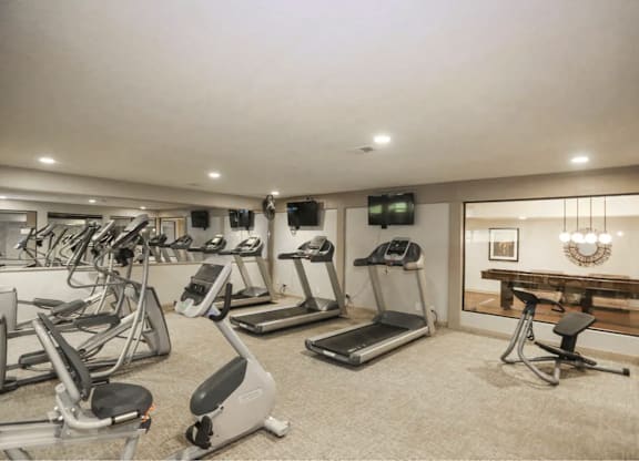 A spacious gym with treadmills, exercise bikes, and a television.