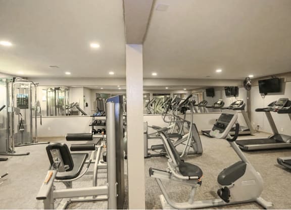 A well-lit gym with a variety of exercise equipment.