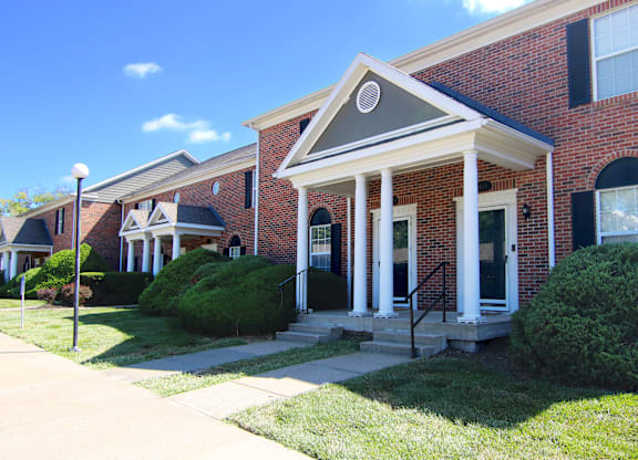 A red brick house with a white front porch.
