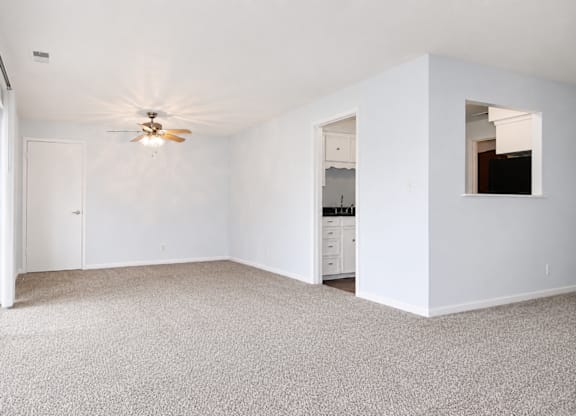 A room with a ceiling fan and carpeted floor.