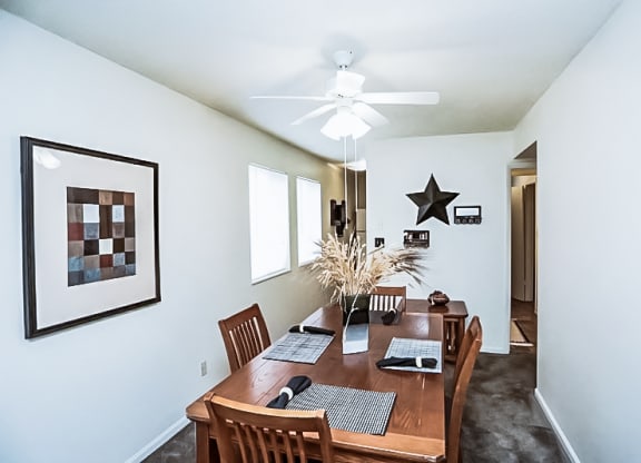 a dining room with a wooden table and a ceiling fan at Gatehouse Apartments, Kansas City, MO, 64134