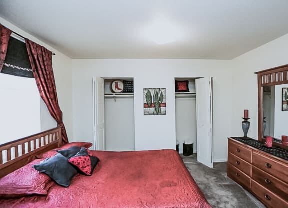 a bedroom with a red bed and a dresser at Gatehouse Apartments, Kansas City, MO, Missouri, 64134