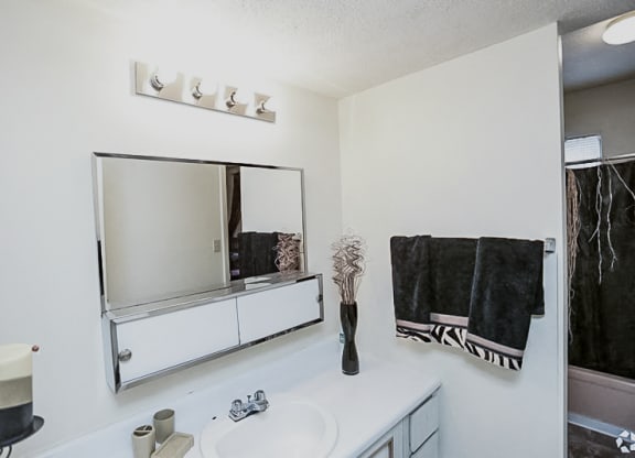 a bathroom with a sink and a mirror at Gatehouse Apartments, Kansas City