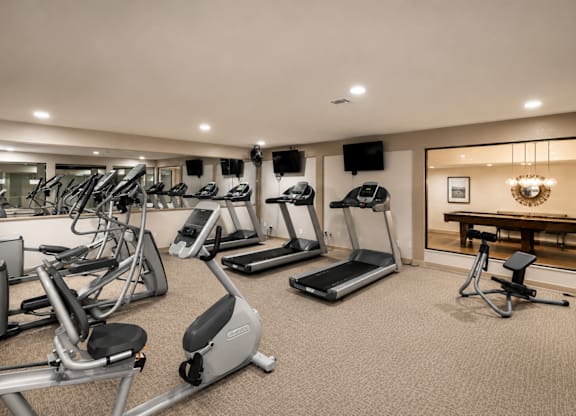 A well-lit gym with a variety of exercise equipment.