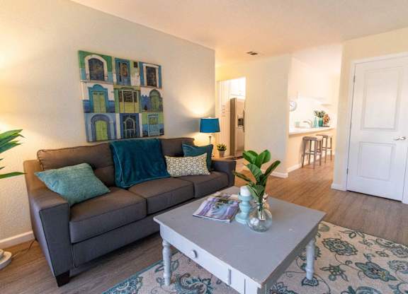 A living room with a grey couch, a grey coffee table, and a green plant.