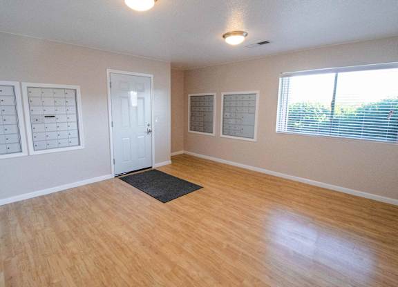 A room with a wooden floor and a black mat in the middle.