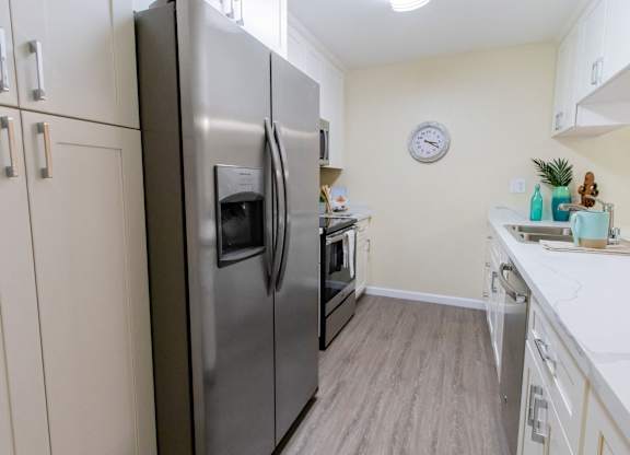 A kitchen with a stainless steel refrigerator and wooden flooring.