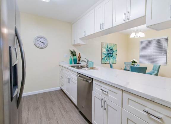 A kitchen with white cabinets and a marble countertop.