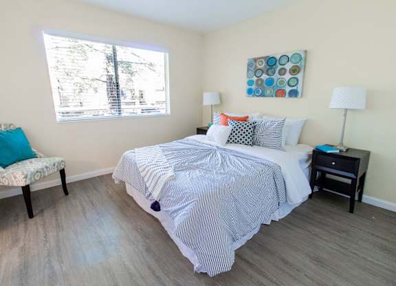 A bedroom with a bed, chair, and lamp.