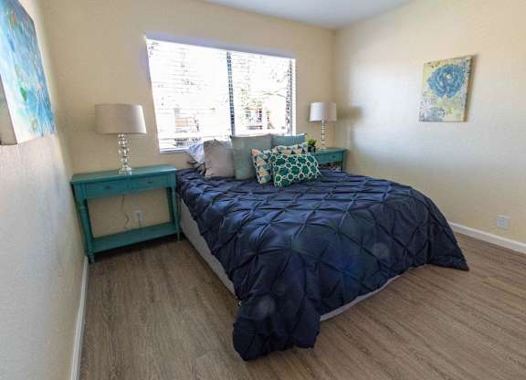 A bedroom with a bed, nightstand, and two lamps.