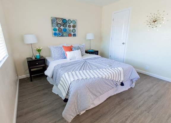 A bedroom with a bed, nightstands, and a painting on the wall.