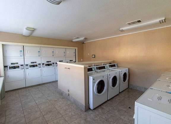 A laundry room with a row of washing machines.