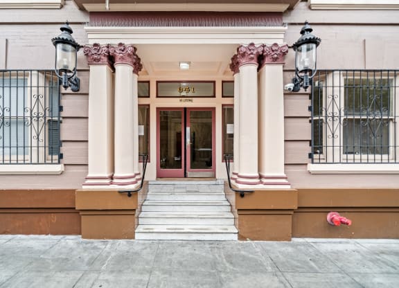 the front of a building with a red door and columns